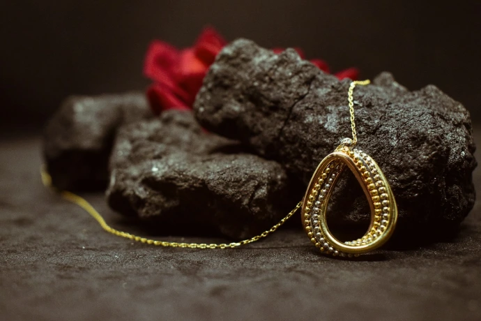 gold necklace on black rock